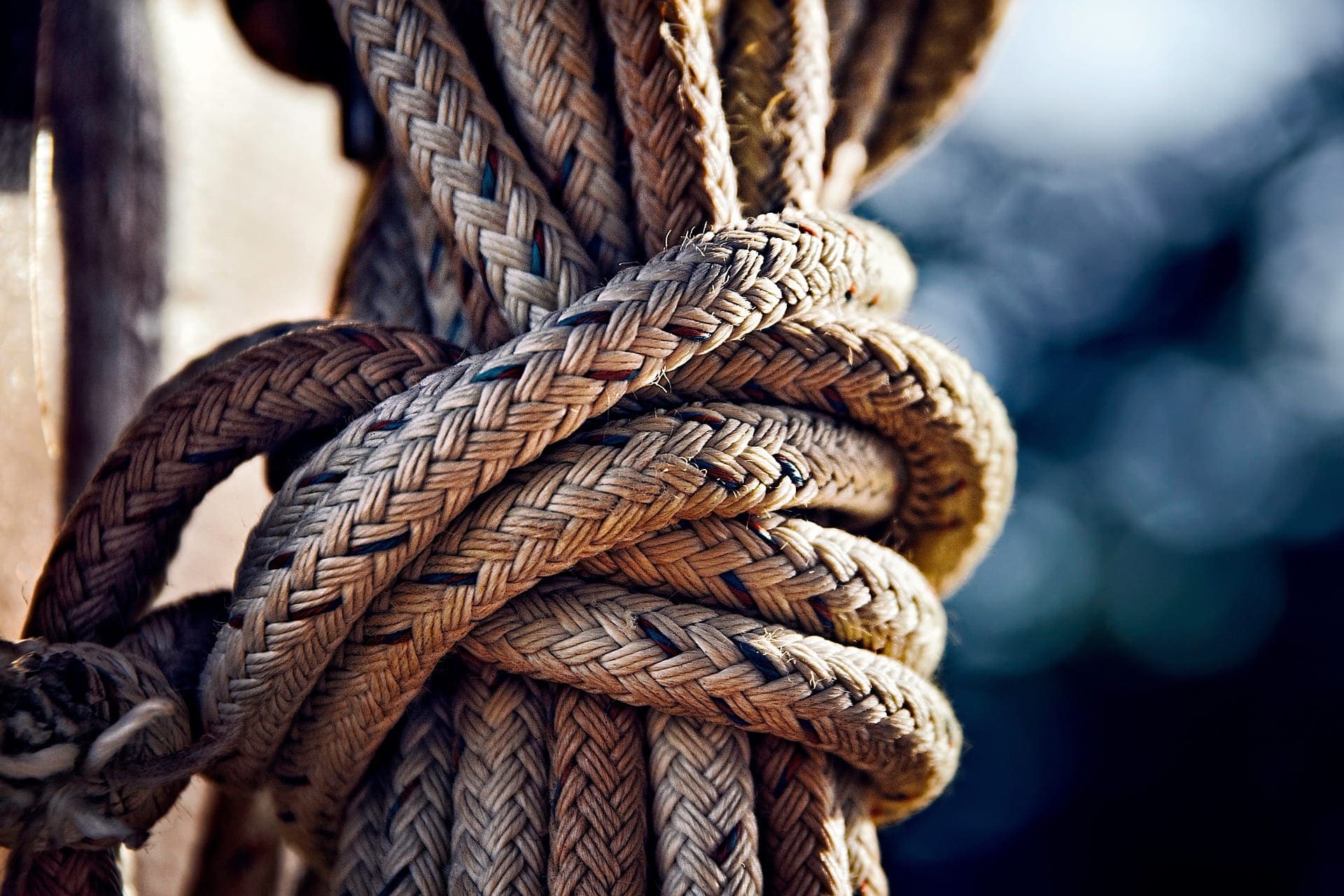 Braided rope secured in a figure-eight pattern around a horn cleat on a yacht deck — a cleat is the twin-horned fitting used to hold a line quickly and securely without a knot